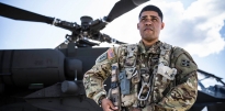 Soldier standing in front of a AH-64 Apache helicopter Soldier standing in front of a AH-64 Apache helicopter